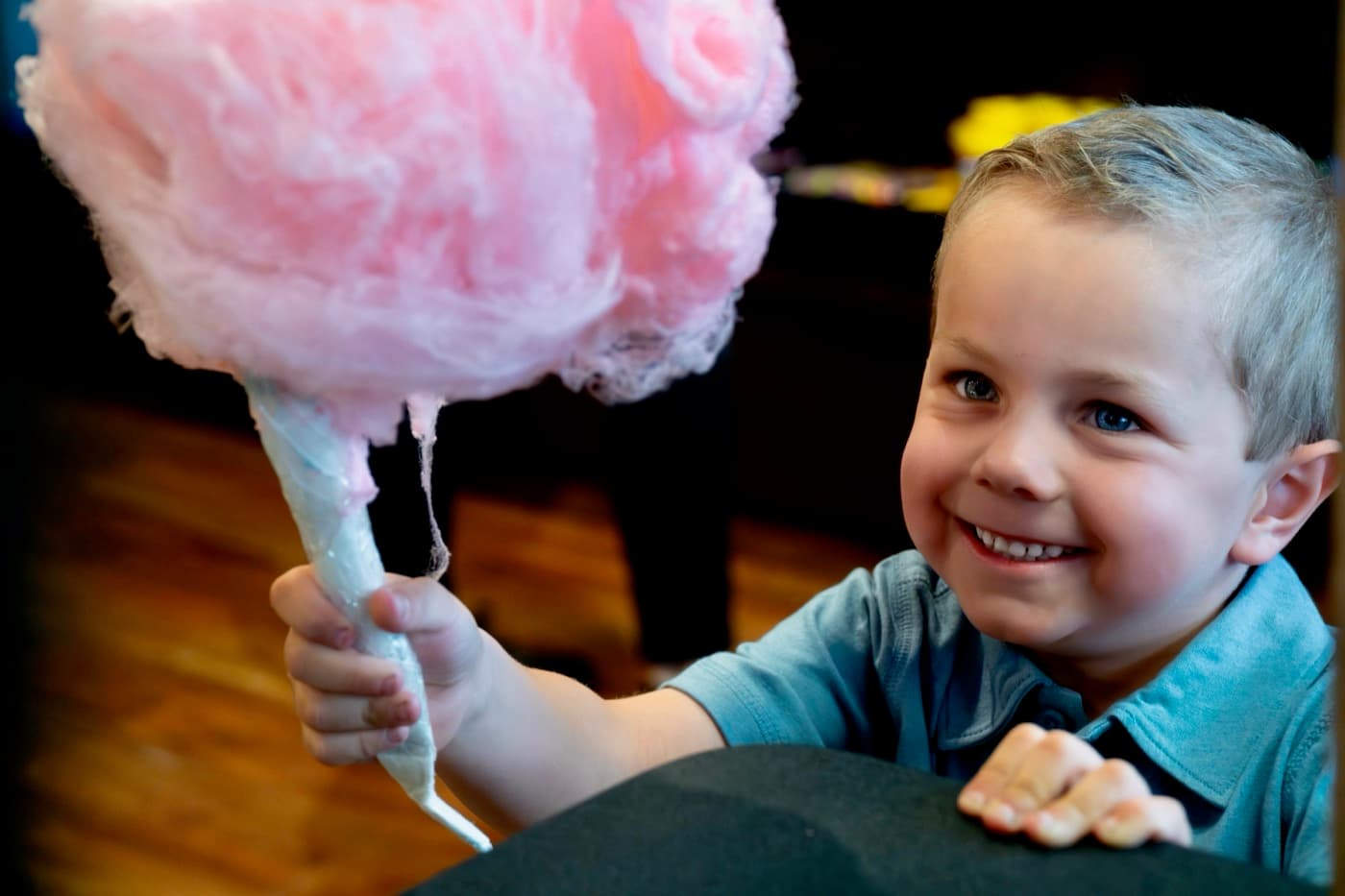 A boy grinning behind a giant pink cotton candy